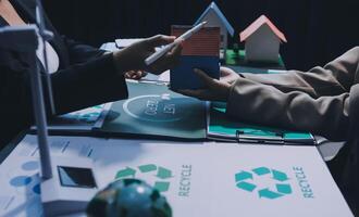 Two people are holding a house model and a sign that says recycle photo