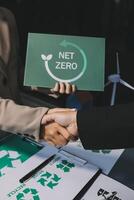 Two people shaking hands over a net zero sign photo