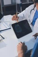 Two doctors are looking at a tablet computer with a brain scan photo