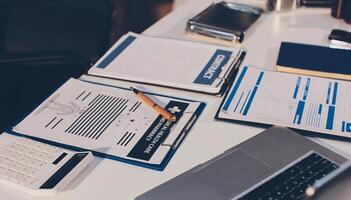A laptop, a pen, a calculator and a notepad are on a desk photo