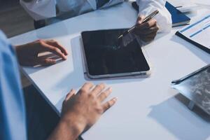 A doctor is using a tablet computer while sitting at a table photo