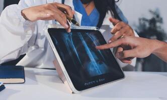 A doctor is examining an x - ray on a tablet photo
