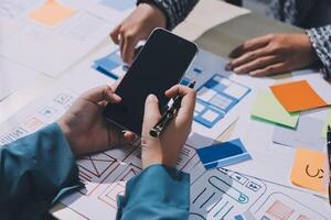 A person is using a cell phone on a table with other papers photo