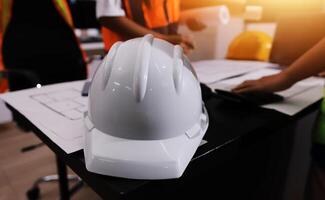 A hard hat sitting on a table with two people photo