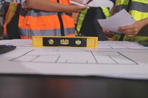 A group of construction workers standing around a table with a construction plan photo
