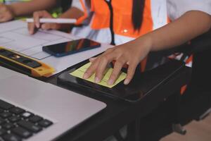 A person in an orange vest and safety vest is working on a laptop photo