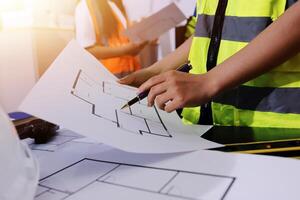 A person in a safety vest and hard hat is holding a pencil and drawing on paper photo