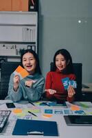 Two young women sitting at a table with paper and scissors photo