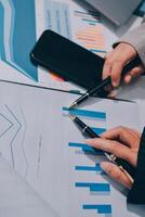 Business people using a pen and a smartphone to look at graphs photo