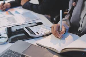 Business people working on a laptop and writing on a notebook photo