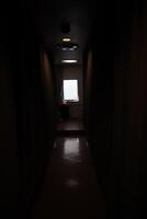 A dark hallway with a light shining through the window photo