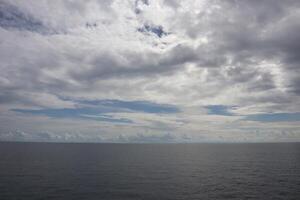 A cloudy sky over the ocean with a boat in the distance photo