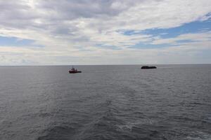 A boat in the ocean with a small boat in the distance photo