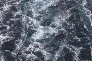 An aerial view of the ocean with white and black waves photo