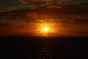 A sunset over the ocean with a boat in the distance photo