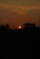 The sun setting over the horizon photo