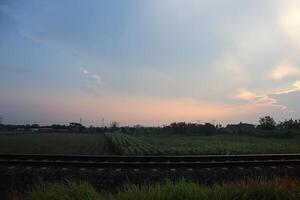 A train is traveling through a field with a sky in the background photo