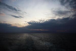 A dark sky with clouds over the ocean photo