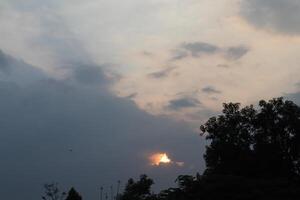 A plane flying in the sky with a sun behind it photo