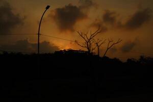 A street light is in the foreground of a sunset photo