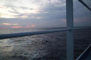 A view of the ocean from a boat at sunset photo