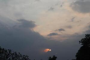 A plane flying through the sky with a sun behind it photo