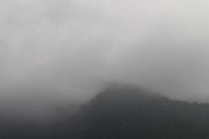 A plane flying over a mountain with fog photo