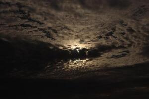 The moon is shining through the clouds in this photo