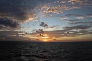 The sun sets over the ocean as seen from the deck of a cruise ship photo