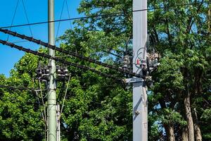 Utility poles and tram power lines are visible against a clear blue photo