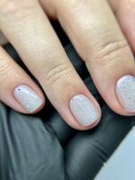 Clean natural manicure on female hand in black glove closeup. photo
