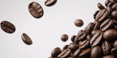 Roasted coffee beans falling and piling up on white background. photo