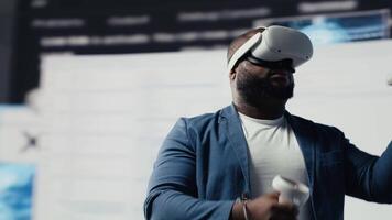 African american software developer uses virtual reality headset for coding, high tech interface workspace. Surrounded by terminal windows, representing digital programming culture. Camera B. video