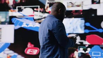 Young black professional explores a tech driven environment with visual data, content feeds and applications. Symbolizing entertainment, social reach and digital transformation. Camera B. video