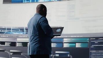 African american skilled engineer programming for innovation hub, reviewing big data and binary code on the dashboard. IT developer working on programming language algorithm. Camera B. video