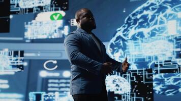 Tech savvy black male engineer reviewing big data AI brain using cloud computing tools and advanced programming for virtual assistant development and IT automation systems. Camera B. video