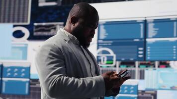 African american specialist checking big data fintech reports on phone app, examining KPI models for financial insight and performance. Young leader browses smartphone. Camera B. video