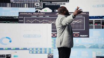 Black leader using digital graphs and analytics to improve finance models for fruitful management decisions. Professional guy optimizing performance with tech intelligence, fintech. Camera A. video