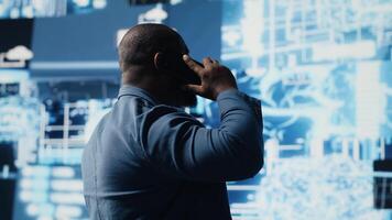 African american IT expert answers phone call to discuss deep learning through neural networks and automation systems. Chatting on telephone line for predictive analytics science. Camera B. video