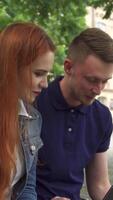 Dynamic duo collaborates on a laptop amidst a vibrant campus backdrop video