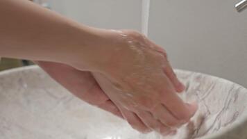 Closeup of hands being washed under running faucet water video
