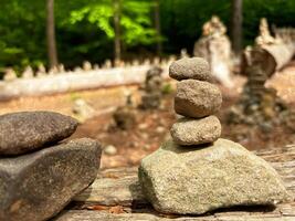 Pyramids are made of small stones in mountainous terrain. Close-up of a stone pyramid standing on a log. photo