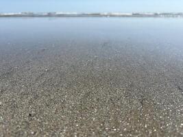 Sparkling sand on a shallow in the Ligurian Sea. Panorama of the seashore with a close-up of the sand. photo