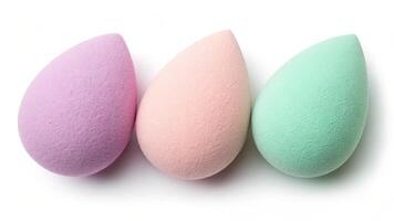 Three pastel colored makeup sponges arranged in a row on a white background photo