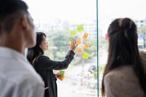 a group of business people standing around a window with sticky notes on them photo