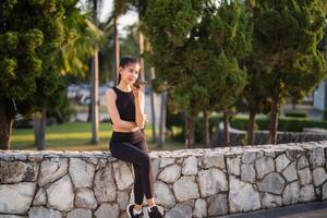 Active healthy asian woman sitting on stone wall in park photo