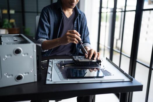 a Engineer installing Hardware working on a computer with a laptop photo