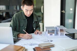 a Architecture Man man is working on a project with a laptop and a model photo