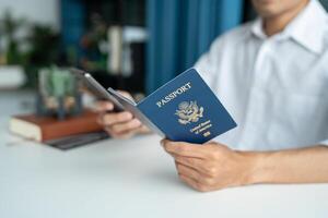 man holding passport and using smartphone at desk photo