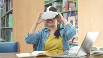 Young Asian female student using virtual reality headset in the library. video